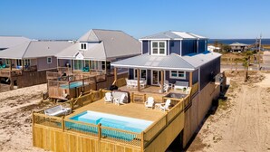 A beachfront property with a pool, deck chairs, and a covered patio. - Blue Pearl | great august rates. Pool. Hottub. On Beach (Dauphin Island)