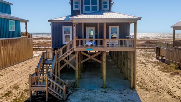 A beach house with a wooden deck and a balcony, featuring a clear view of the ocean. - Blue Pearl | great august rates. Pool. Hottub. On Beach (Dauphin Island)