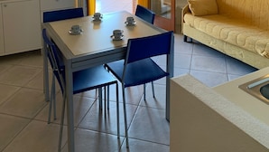 Un espace de vie compact comprenant un coin repas, un canapé et une kitchenette.