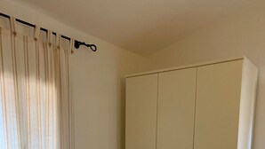 Une chambre à coucher avec un lit, une armoire et un rideau.