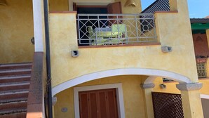 Un bâtiment à deux étages doté d’un balcon, d’une porte en bois et d’un escalier menant à l’entrée.