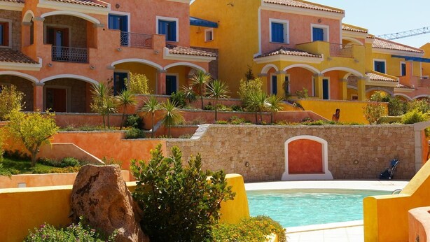 Un hôtel composé de plusieurs bâtiments aux couleurs vives, doté d’une piscine et de jardins aménagés.