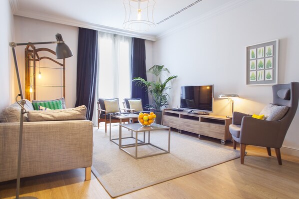 Una sala de estar moderna con sofá, mesa de centro, televisor y una planta.