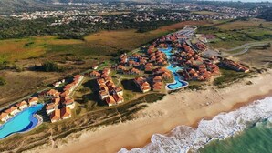 Una vista aerea di una località balneare con diversi edifici, una piscina e una spiaggia.