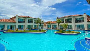Um resort com uma piscina central ampla, rodeada por vários edifícios com varandas e áreas de estar ao ar livre.