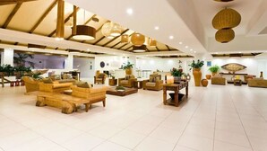 Un'ampia hall con mobili in vimini, un soffitto alto con lampade a sospensione e un design d'interni moderno.