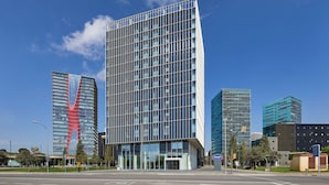 Un edificio moderno con fachada de vidrio, situado en una intersección urbana.