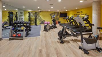 Un gimnasio con cintas de correr, bicicletas estáticas, mancuernas y pesas.