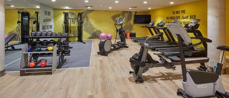 A gym with treadmills, exercise bikes, kettlebells, and dumbbells.