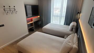 Una habitación de hotel moderna con dos camas, televisión y escritorio.