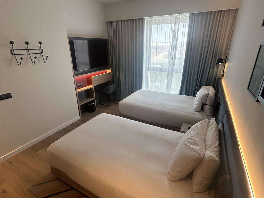 Una habitación de hotel moderna con dos camas, televisión y escritorio.