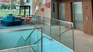 Un interior moderno con una escalera de cristal, zona de estar y ascensores.