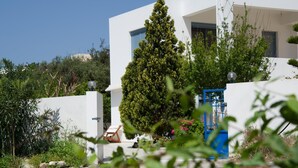 A modern white building with a blue door, surrounded by greenery and a clear sky. - Family Holidays House Koutsouras by GHH (Ierapetra)