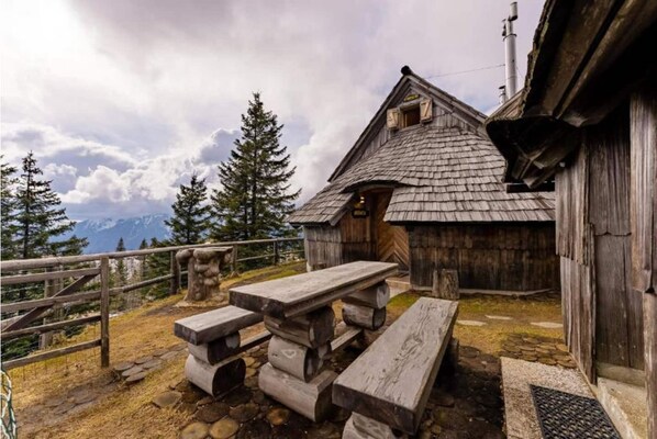 A rustic wooden cabin with a sloped roof, a wooden bench, and a picnic table.