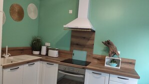 Une cuisine avec des armoires blanches, un plan de travail en bois, une cuisinière blanche et une hotte aspirante blanche.