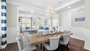 Un comedor con una mesa de madera, seis sillas tapizadas, cristalería decorativa y un candelabro.