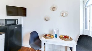 A compact kitchen with a microwave, refrigerator, and a dining area with a table set for breakfast. - Sweett | Arco della Pace (Milano)
