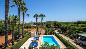 A rectangular swimming pool with a paved deck, surrounded by palm trees and well-manicured hedges. - Villa Pantina, 2 bedroom villa near Pollensa (Port de Pollença)