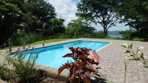 A swimming pool surrounded by lush greenery and a view of a lake. - VillasvistaMasaya, double detached bungalow with access to swimming pool (Masatepe)