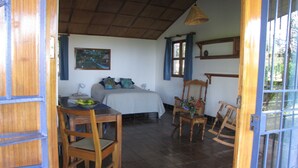A room with a bed, a table with fruit, a chair, and a wooden chair. - VillasvistaMasaya, double detached bungalow with access to swimming pool (Masatepe)