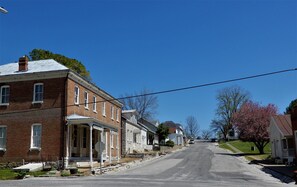 A quiet street lined with historic brick buildings, including a general store with a porch. - Peter Ray House (Maeystown)