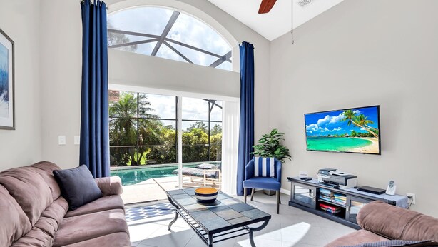 Ein geräumiger Wohnbereich mit großem Fenster, Pool und Flachbildfernseher.