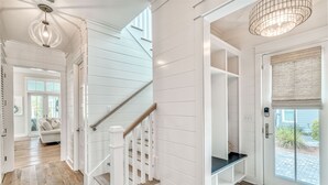 Un escalier avec des rampes blanches et une main courante en bois, menant à un palier doté d’un banc intégré et d’une porte avec une fenêtre.