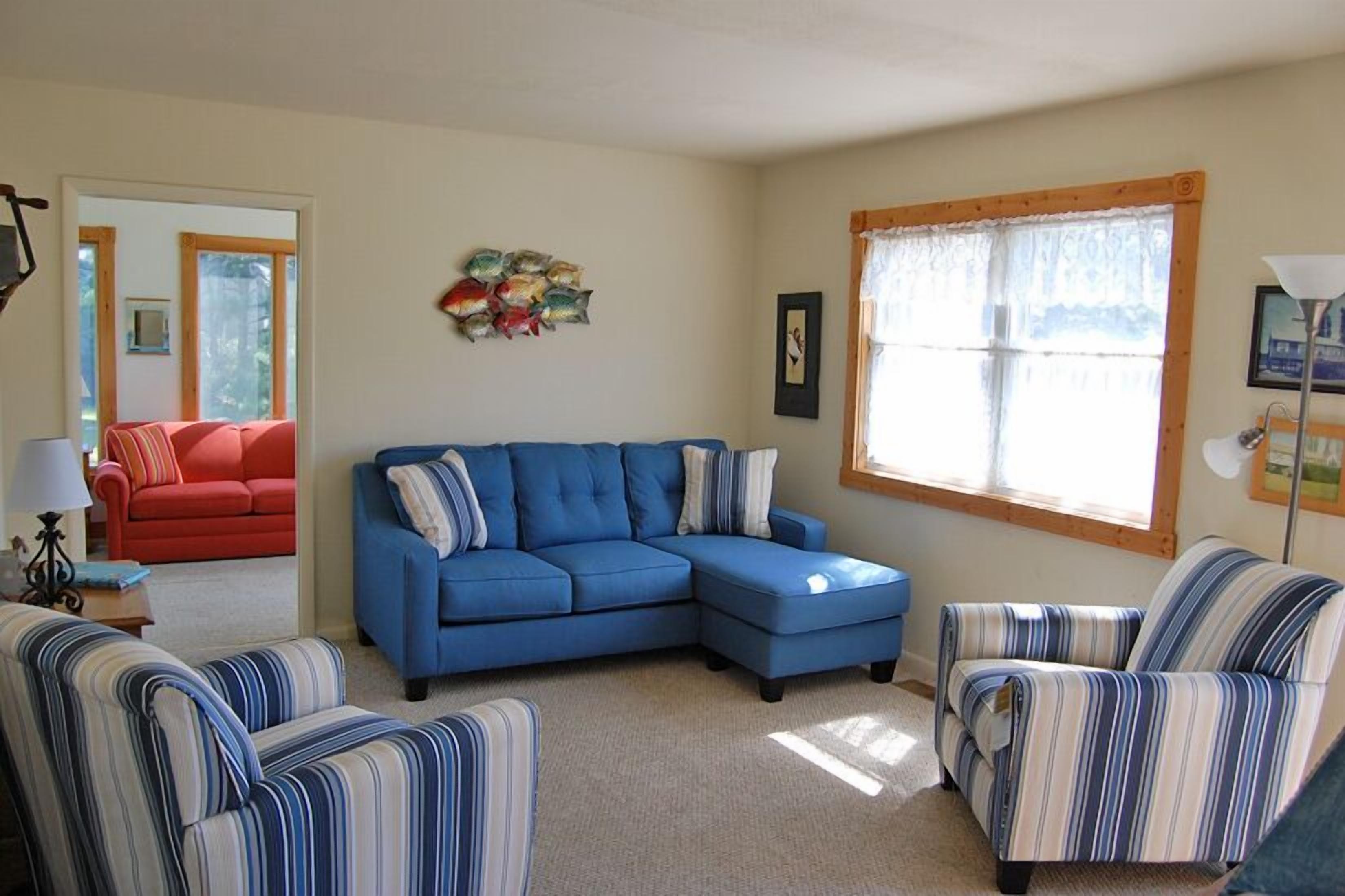 A living room with a blue sectional sofa, striped armchairs, and a red couch.