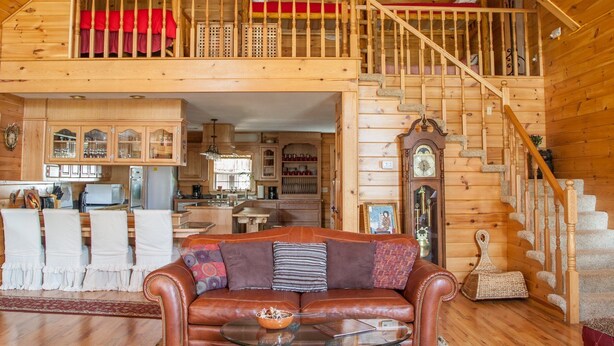 Un vaste espace de vie aménagé dans un style industriel, avec un escalier en bois, un coin repas et une cuisine.