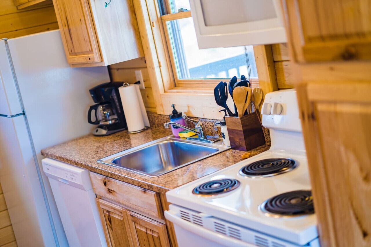 A kitchen with wooden cabinets, a white stove, a sink, and a coffee maker.