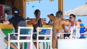 Een strandbar met houten meubilair en een rieten dak.