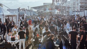 Een druk evenement buiten, met tafels en stoelen klaar voor eten.