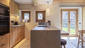 A modern kitchen with a central island, wooden cabinets, and a built-in Bosch oven. - Luderna - Apartamento con jardín Crabera (Arties)