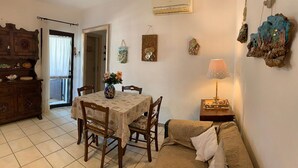 A cozy living room with a dining table, chairs, a sofa, and a lamp. - L'oasi DI Orosei (OROSEI-NUORO)