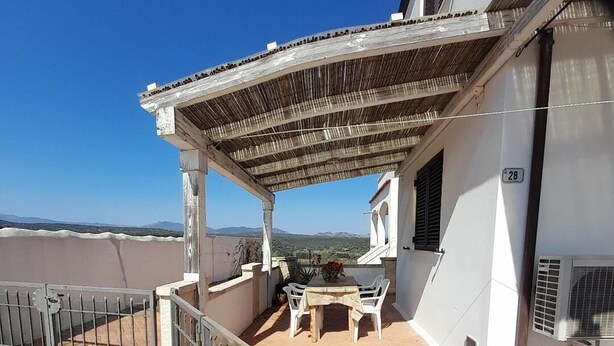 A covered outdoor patio with a table and chairs, a pergola, and a view of the landscape. - L'oasi DI Orosei (OROSEI-NUORO)