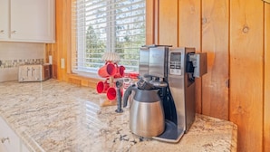 A kitchen with a coffee maker, toaster, and red mugs on the counter.