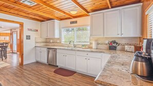 A modern kitchen with white cabinets, a granite countertop, and a stainless steel coffee maker.