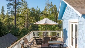 A deck with outdoor furniture, a grill, and a large umbrella.