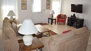 Un salon comprenant un canapé, une table basse, un téléviseur et deux lampes.