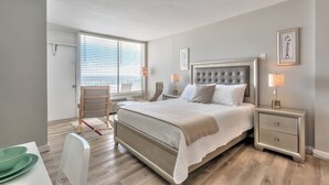 Une chambre à coucher avec un grand lit, des tables de chevet, une chaise et un bureau.