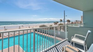Un balcon avec vue sur une plage et une piscine.