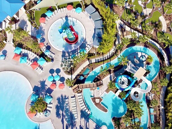 An aerial view of a resort with multiple swimming pools, sun loungers, and umbrellas.
