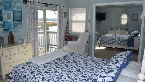 Un dormitorio con cama, una silla, un tocador y un armario.