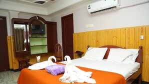 A hotel room with a bed, a television, a mirror, and a wardrobe. - Hotel Nandha (Karaikal)