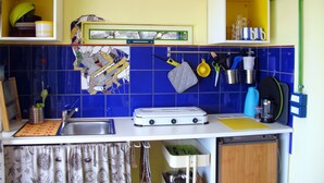 A kitchen with a tiled backsplash, a stove, a sink, and various utensils hanging on the wall. - Simply put...vacation (Frontera)
