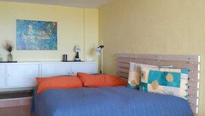 A bedroom with a bed, a headboard, a nightstand, a lamp, a painting, and a window. - Simply put...vacation (Frontera)