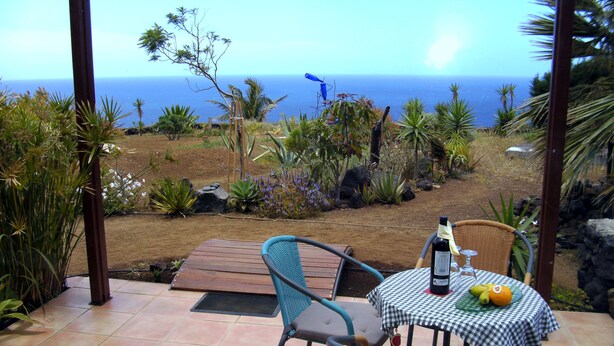 An outdoor patio with a table and chairs, a bottle of wine, and a fruit bowl. - Simply put...vacation (Frontera)