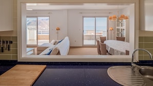 A modern kitchen with a large window, a sink, and a dining area with a table and chairs. - HAYMAN II          . (Ventorros de San José)