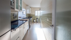 A modern kitchen with stainless steel appliances, a black countertop, and light-colored tiles. - HAYMAN II          . (Ventorros de San José)