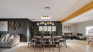A modern living room with a dining table, sofas, and a large window.